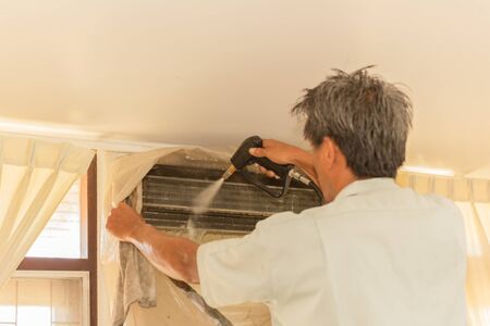 Worker cleaning wall air conditioner with high pressure water jet pump at home.の写真素材