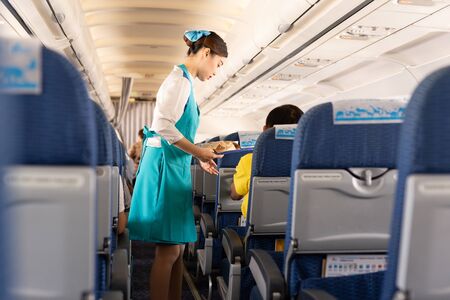 BANGKOK, THAILAND - June 27, 2019 - Bangkok Airways flight attendant serve food to passengers on board.のeditorial素材
