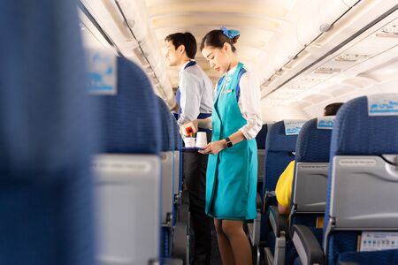 BANGKOK, THAILAND - June 27, 2019 - Bangkok Airways flight attendant serve food to passengers on board.のeditorial素材