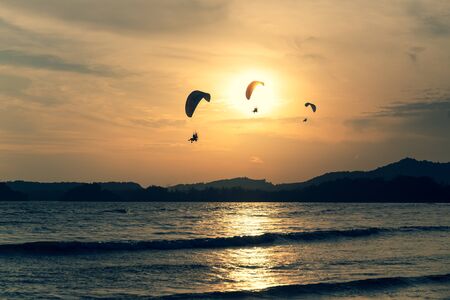 Beautiful Silhouette of paraglider flying in the sky of sunset on the beach.の写真素材
