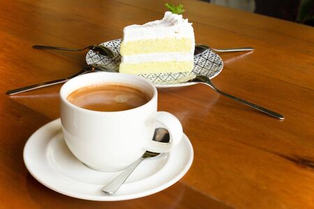 Cup of coffee with piece of cake on wooden table in cafe.の写真素材