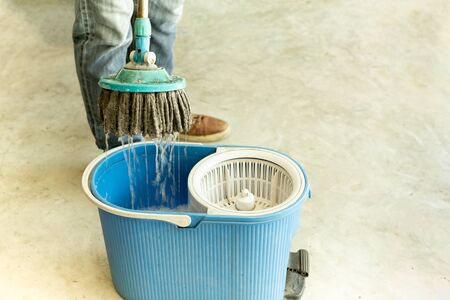 Man worker with mop and bucket cleaning floor in the cafe.の写真素材