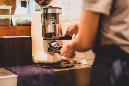 Barista grinding fresh coffee beans using coffee machine.の写真素材