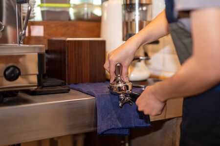 Barista with tamper and piston, port filter making fresh coffee.の写真素材