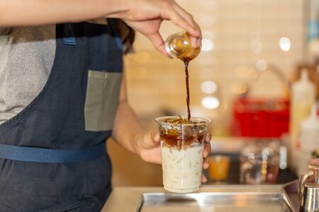 Barista pouring coffee to takeaway cup to making iced coffee latte in the cafe.の写真素材