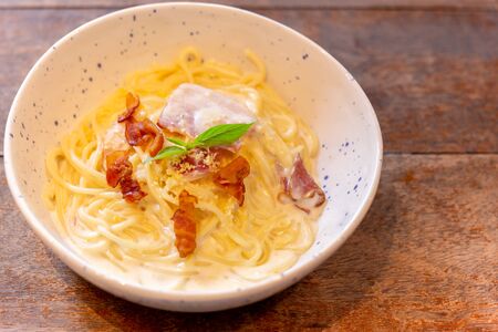 Spaghetti carbonara with bacon and ham on wooden table.の写真素材
