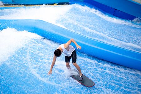 Unidentified man playing surfboard indoor extreme sport.の写真素材