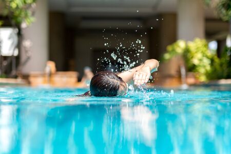 Unidentified woman doing front crawl swimming in swimming pool on vacation.の写真素材