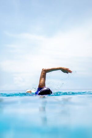 Unidentified woman doing front crawl swimming in swimming pool on vacation.の写真素材