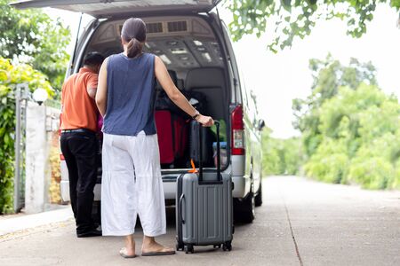 Woman holding luggage with driver putting luggage in mini bus travel concept.の写真素材