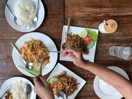 Top view woman hand holding spoon with pad tai noodle and rice on wooden table.の写真素材