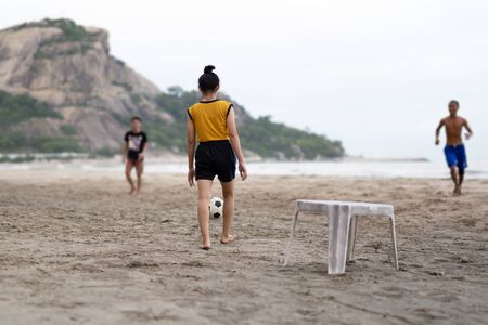 Selected focus group of friends playing soccer on the beach in summertime.の写真素材