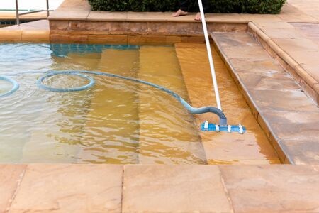 Worker cleaning swimming pool with vacuum tube in the morning.の写真素材
