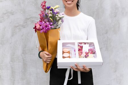 Portrait of cheerful woman holding flowers and gift box.の写真素材
