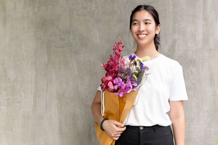 Portrait of cheerful pretty woman holding flowers over gray background.の写真素材
