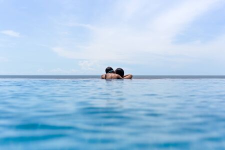 Mother and young son relax in swimming pool looking over the ocean on summer vacation.の写真素材