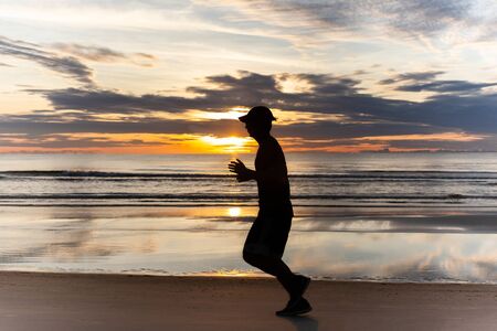 Unidentified man running on the beach at sunset.の写真素材