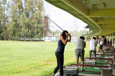Asian woman practicing his golf swing at the golf driving range.の写真素材