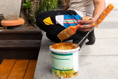 Worker hand dipping brush tool in varnishing can.の写真素材