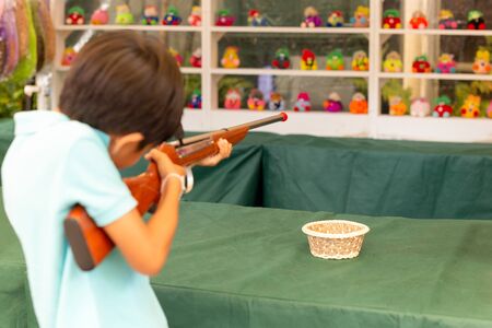 Boy shooting cork gun game at fair.の販売画像