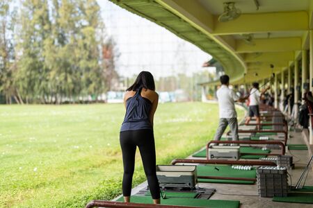 Asian woman practicing his golf swing at the golf driving range.の写真素材