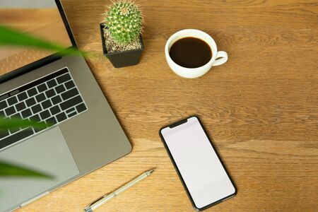 Business object cell phone and coffee cup with laptop and pen on wooden desk.の写真素材