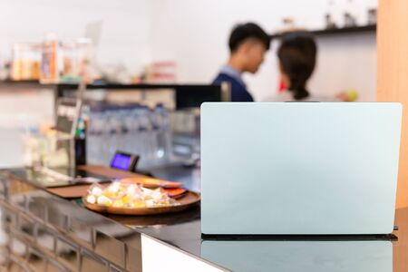 Laptop on counter coffee bar with barista working in blurredの写真素材
