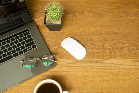 Top view of office desk with laptop, eyeglasses, mouses and cup of coffee.の写真素材