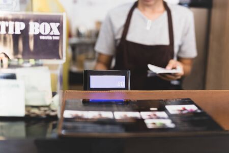 Selected focus cashier register with female waitress operating in cafe.の写真素材