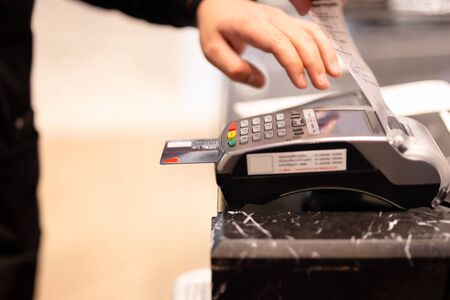 Male cashier hand put credit card in cash register for customer payment.の写真素材