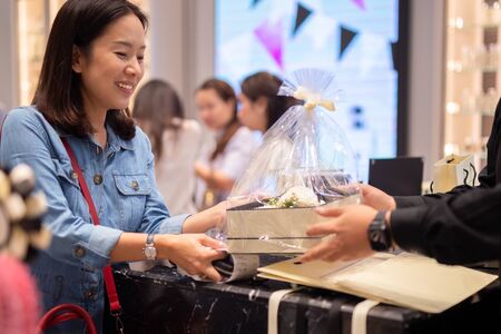 Happy woman customer receiving gift and flower boxset from shop manager.の写真素材