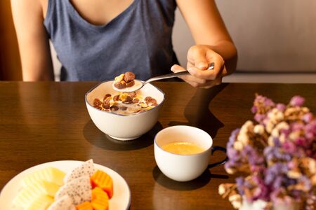 Healthy woman eating corn flakes cereal and coffee for breakfast on table.の写真素材