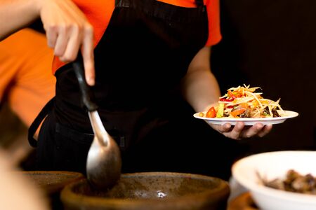 Woman making Thailand spicy papaya salad with crab in restaurant.の写真素材