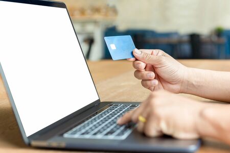 Businessman hand holding credit card and using laptop on wooden table.の写真素材