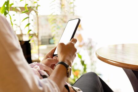 Woman using cellphone wooden typing text message in coffee shop.の写真素材
