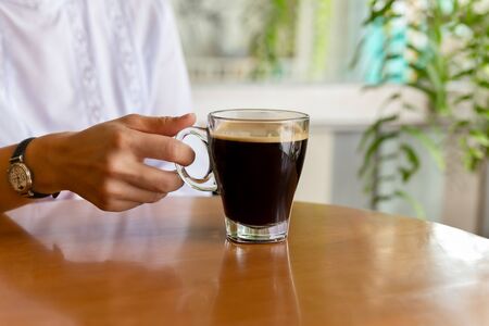 Woman holding warm mug of fresh coffee in cafe.の写真素材