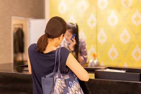 Woman at checkout in clothing store with staff on the phone enquiry.の写真素材