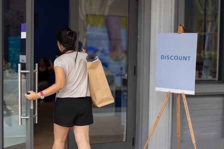 Unidentefied woman with paper shopping bags entering the shop.の写真素材