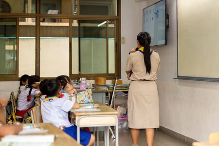 Back view of asian teacher stand in front of class and teaches students.の写真素材