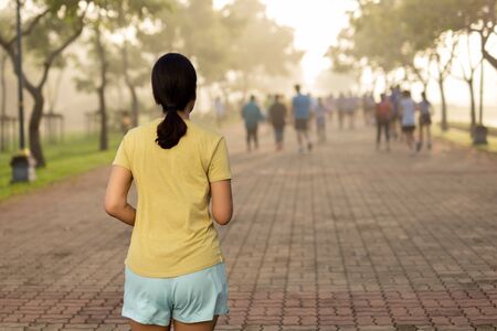 Woman exercise jogging in park with blurred peopleの写真素材
