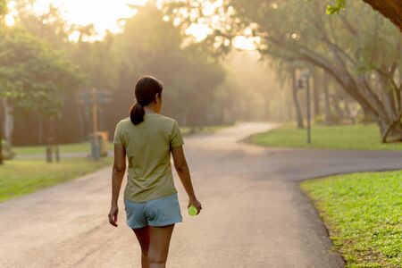 Woman exercise walking in the park with bottle water at sunriseの写真素材