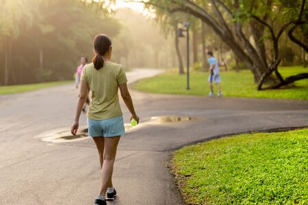 Woman exercise walking in the park with bottle water at sunriseの写真素材
