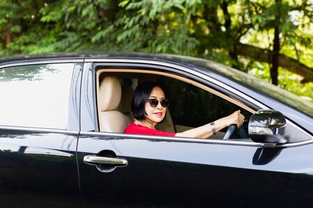 Happy senior woman in sunglasses driving a car.の写真素材