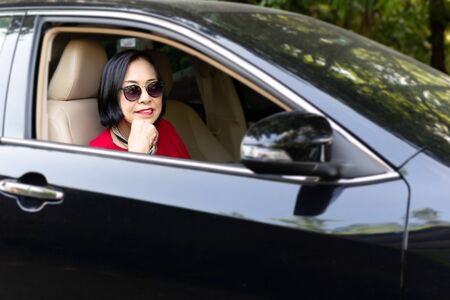 Happy smiling senior woman sitting in a car.の写真素材