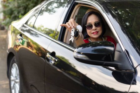 Happy senior woman driving and showing her new car key.の写真素材
