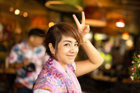 Happy smiling woman portrait of playful funny positive with two finger up.