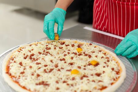 Chefs hand preparing pizza on kitchen table top with quail eggの写真素材