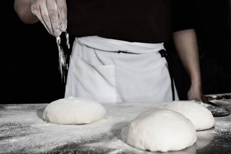 Chef prepares the dough with flour to make a pizza.の写真素材