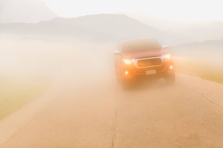 Driving cars in the fog mountain wuth headlight beams in dense mistの写真素材