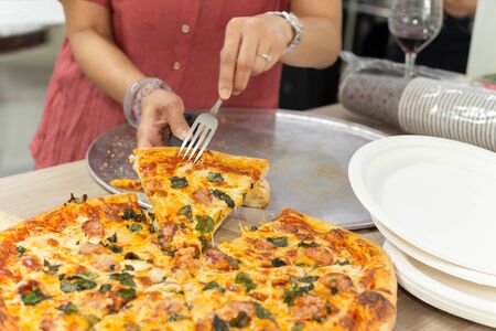 Woman hands using fork taking slices of pizza at dinner party.の写真素材
